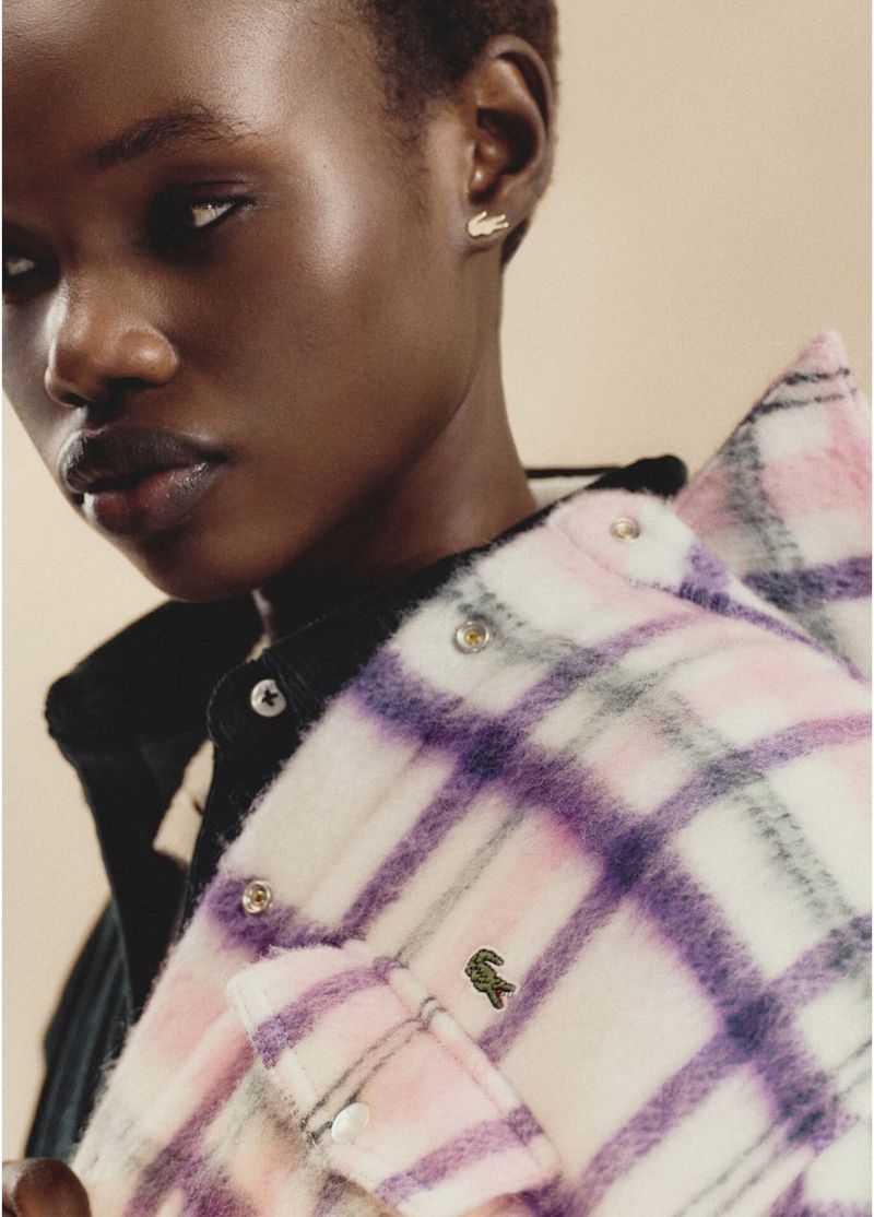 Close-up of an African American woman wearing a plaid jacket with a Lacoste logo, showcasing fashion and style.