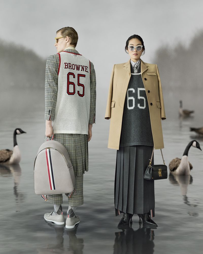Two fashion models pose in a serene lake setting, wearing basketball jerseys and formal attire. Canada geese float on the water.