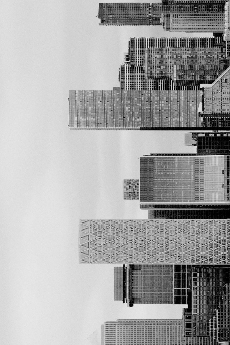 Monochrome view of a high-density cityscape featuring modern architecture, tall buildings, and skyscrapers against a light grey sky.
