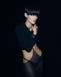 Model with short dark hair in black apparel posing against a black background for Tom Ford S/S 2026