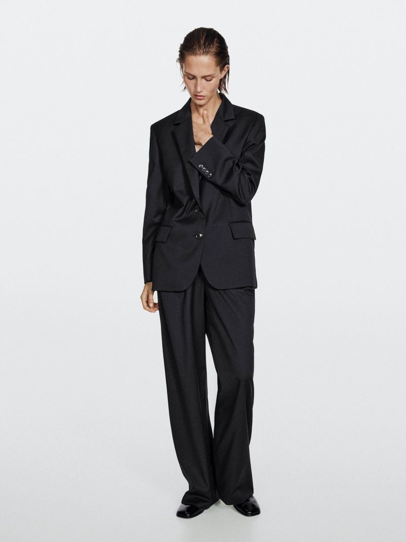 Model in a black suit standing against a plain light grey background for Massimo Dutti