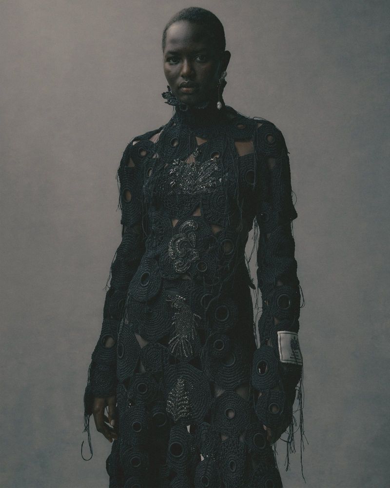 Elegant portrait of a Black female model in an openwork dress against a neutral background, capturing a blend of fashion and fine art.