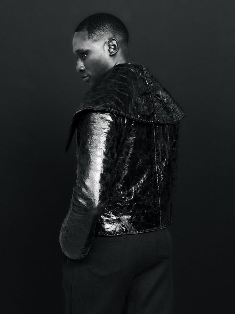 Portrait of a Black man in a reptile-patterned jacket against a dark backdrop, showcasing fashion and portrait photography.
