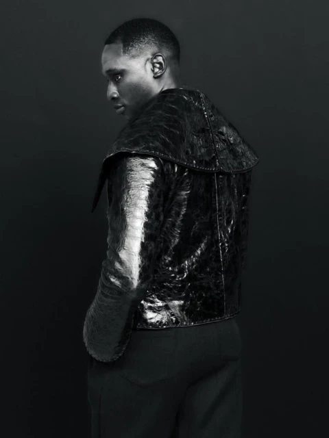 Portrait of a Black man in a reptile-patterned jacket against a dark backdrop, showcasing fashion and portrait photography.