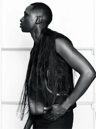 Profile portrait of a male model wearing a dark fringe vest against a white studio background for the Kent Anthony S/S 26 Lookbook