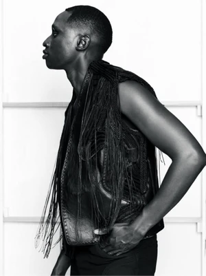 Profile portrait of a male model wearing a dark fringe vest against a white studio background for the Kent Anthony S/S 26 Lookbook