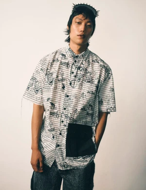 Model in printed graphic shirt with black pocket wearing a spiked headpiece against a neutral background