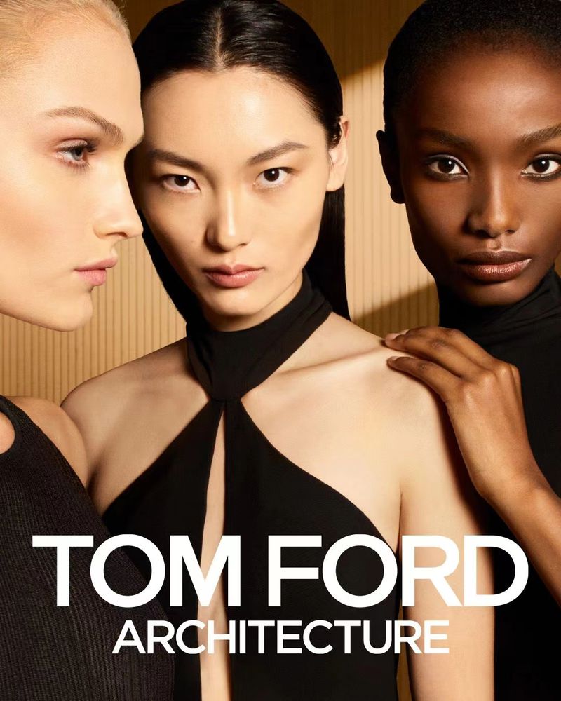 Close-up shot of three women with different skin tones, wearing elegant black tops, against a textured tan background. Beauty and fashion.