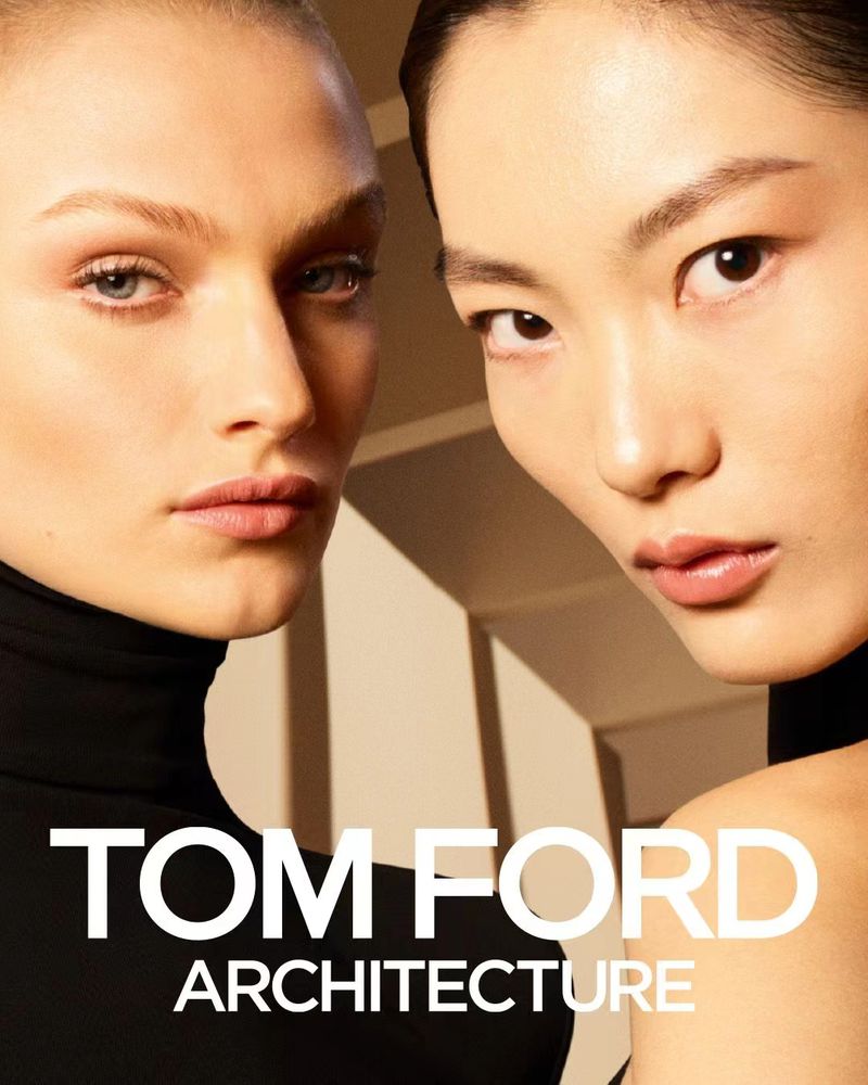 Two adult women pose in a beauty shot for an advertisement, wearing black turtlenecks with 'TOM FORD ARCHITECTURE' text overlay.