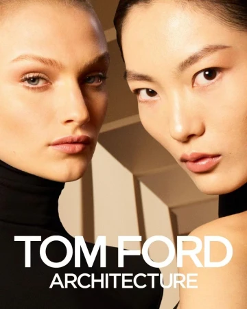 Two adult women pose in a beauty shot for an advertisement, wearing black turtlenecks with 'TOM FORD ARCHITECTURE' text overlay.