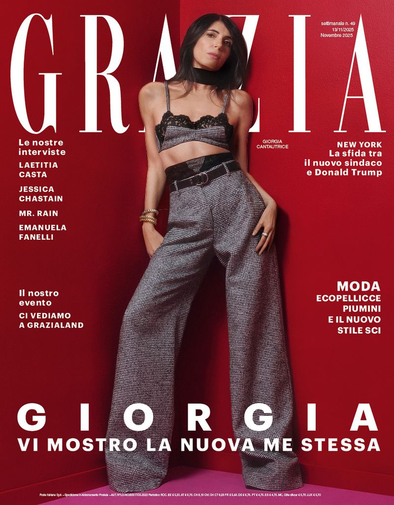 Magazine cover featuring a full-length shot of a model wearing a two-piece set and wide-leg pants against a red backdrop.