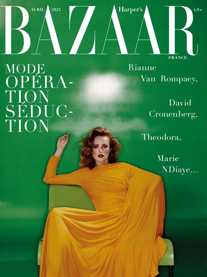 Fashion magazine cover featuring a woman in a yellow dress sitting in a chair against a green background with white text overlay.
