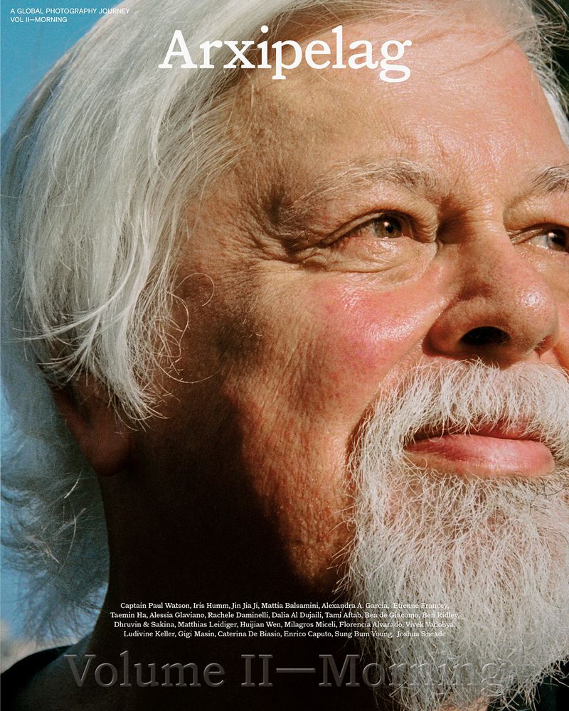 Close-up portrait of an older adult man with long white hair and a beard, smiling slightly. Arxipelag Volume II-Morning