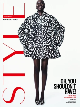 Model Adut Akech in a black and white patterned coat against a white background for The Sunday Times Style Magazine