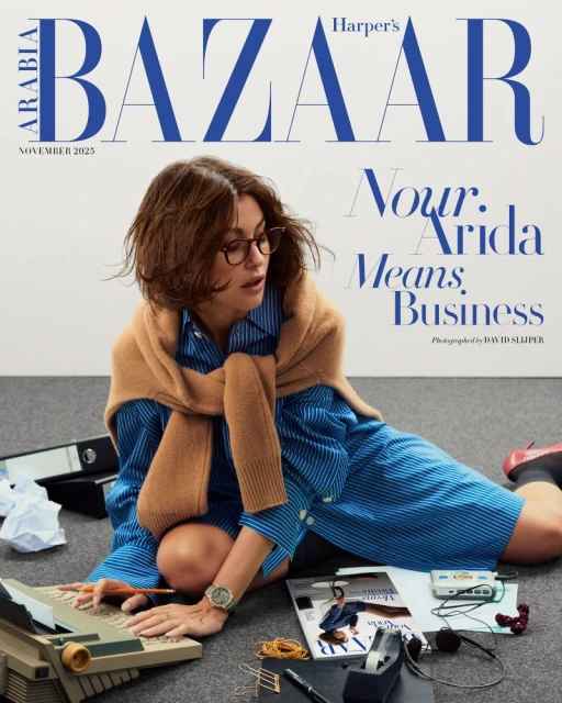 Harper's Bazaar Arabia cover, November 2023 issue. Woman with glasses types on vintage computer surrounded by office supplies.