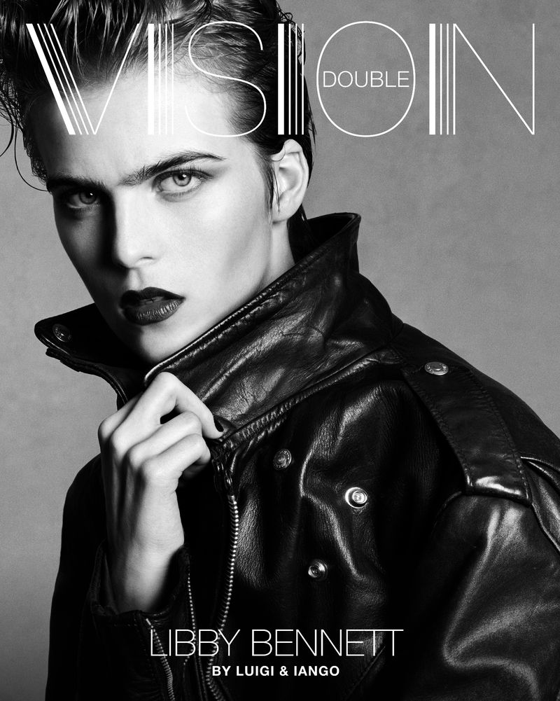 Black and white portrait of a woman with slicked-back hair, wearing a leather jacket, against a plain background, fashion editorial.