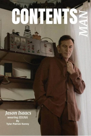Man wearing a brown suit poses indoors next to a vintage electronic device; magazine-style cover with bold text and designer credit.