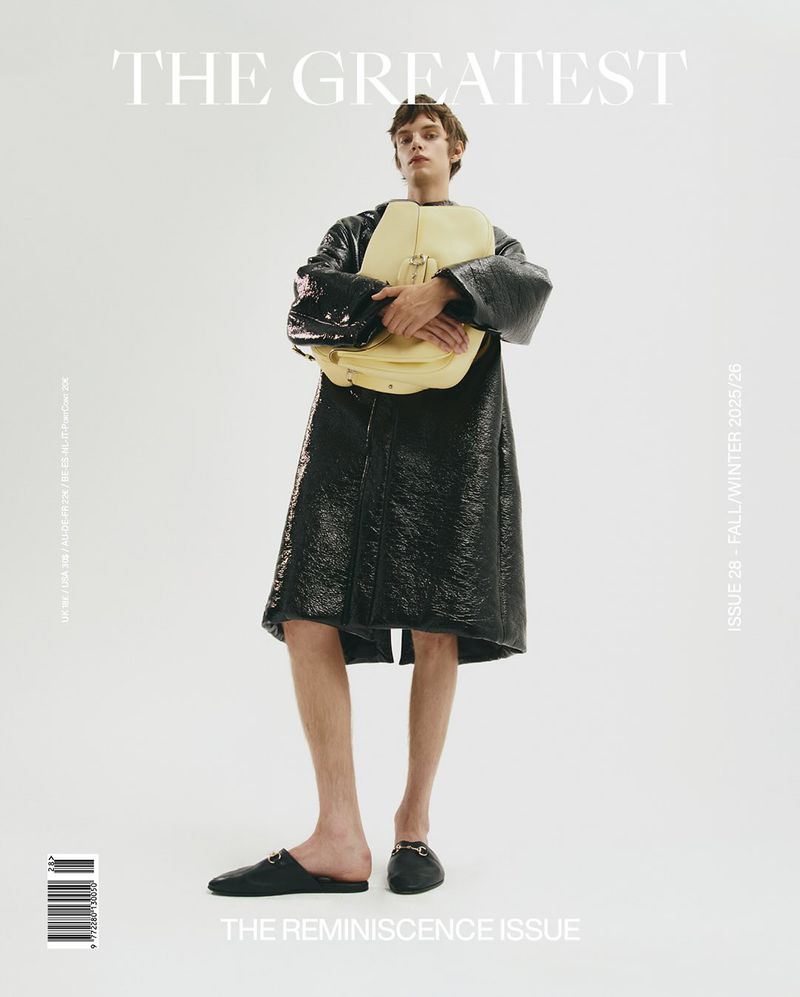 Fashion magazine cover featuring a male model in a black coat holding a yellow bag, set against a bright white backdrop with prominent typography.