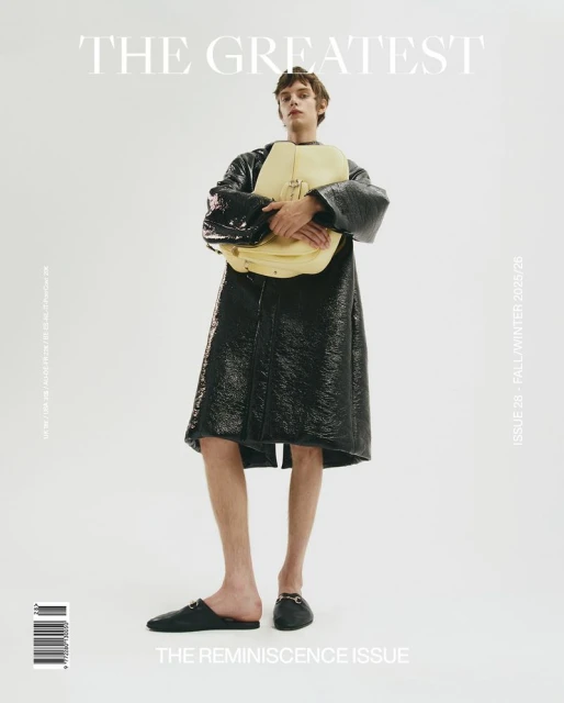 Fashion magazine cover featuring a male model in a black coat holding a yellow bag, set against a bright white backdrop with prominent typography.