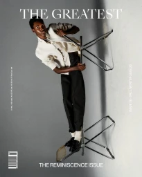 Model in an off-white shirt and black trousers holding a metal folding chair against a grey studio backdrop.