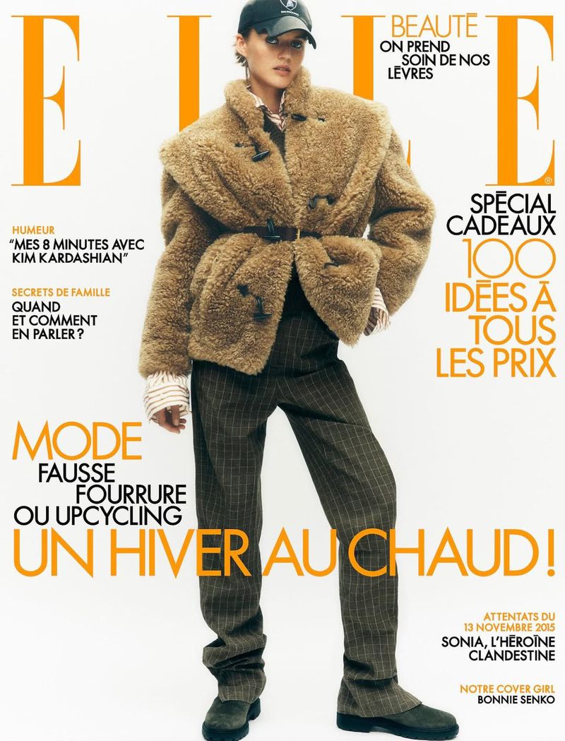 Magazine cover featuring a woman in a shearling coat, pinstripe pants, and a baseball cap, with the magazine's title prominently displayed.