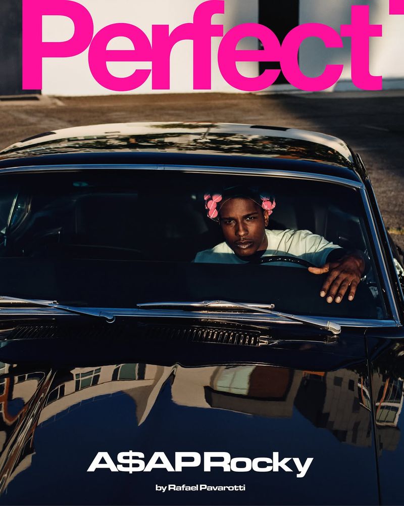 A$AP Rocky sits in a classic black car, bathed in natural sunlight, promoting a magazine cover against an urban backdrop.