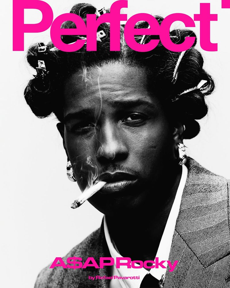 Magazine cover featuring A$AP Rocky smoking a cigarette, wearing hair rollers and a suit against a light grey background with pink text.