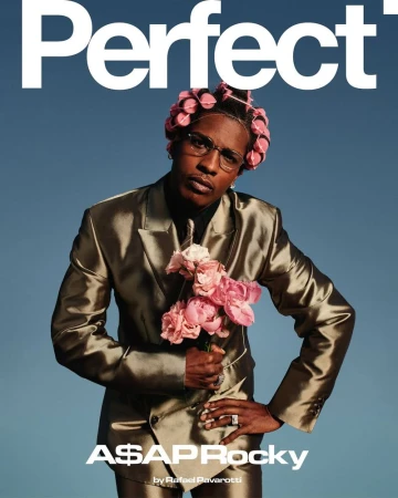 ASAP Rocky magazine cover with pink hair curlers, wearing a gold suit, holding pink flowers, standing against a light blue background.