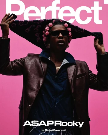A$AP Rocky wearing pink hair rollers, sunglasses, and a leather jacket holding a scarf against a bright pink background.