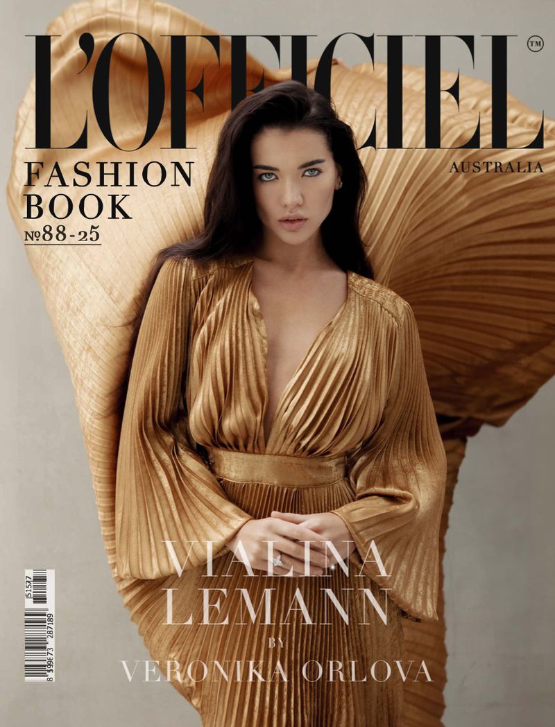 Magazine cover featuring a brunette woman in a gold pleated dress and draped fabric, with the magazine's title, 'L'Officiel' visible.