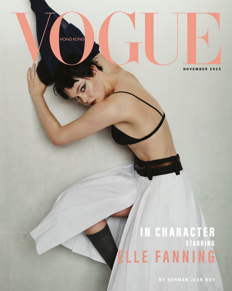 Vogue Hong Kong cover, November 2025, featuring Elle Fanning in black bra and white skirt, leaning against a wall with Vogue masthead.