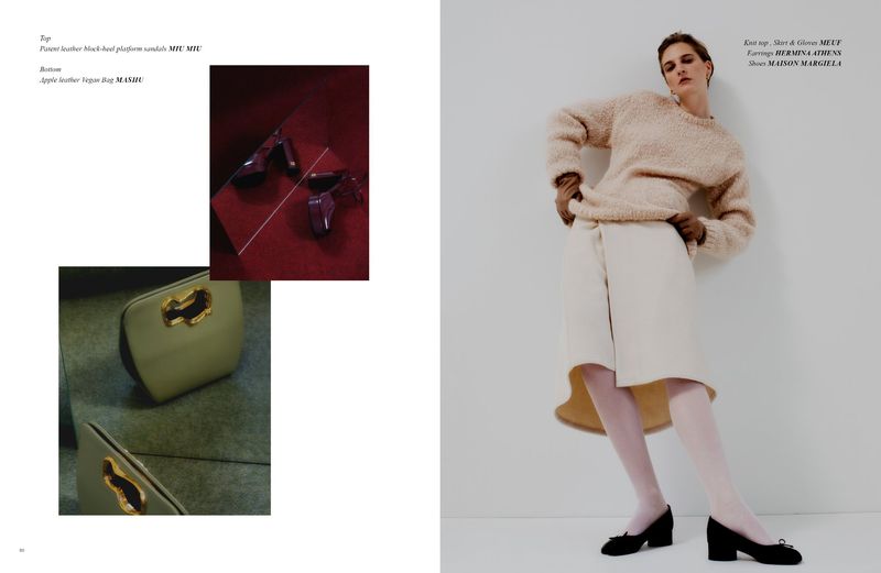 Fashion editorial shot featuring a woman in a beige knit top and white skirt with black shoes, bag and heels accessories in the background.