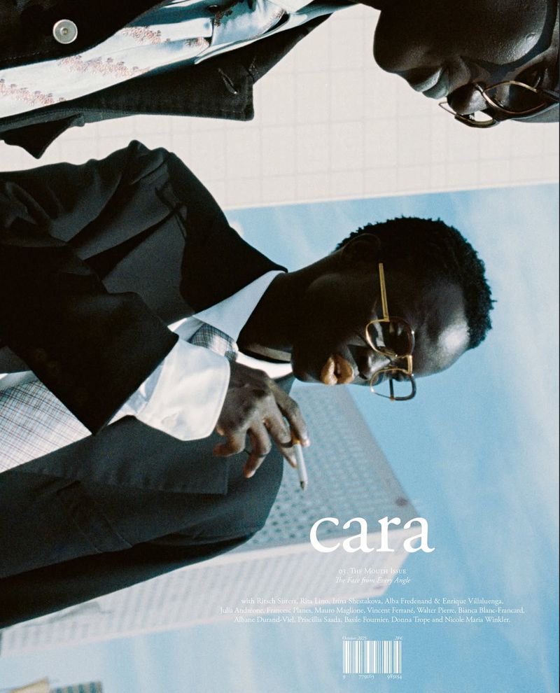 Fashion editorial shot of two Black male fashion models wearing blazers and glasses, with buildings in the backdrop.