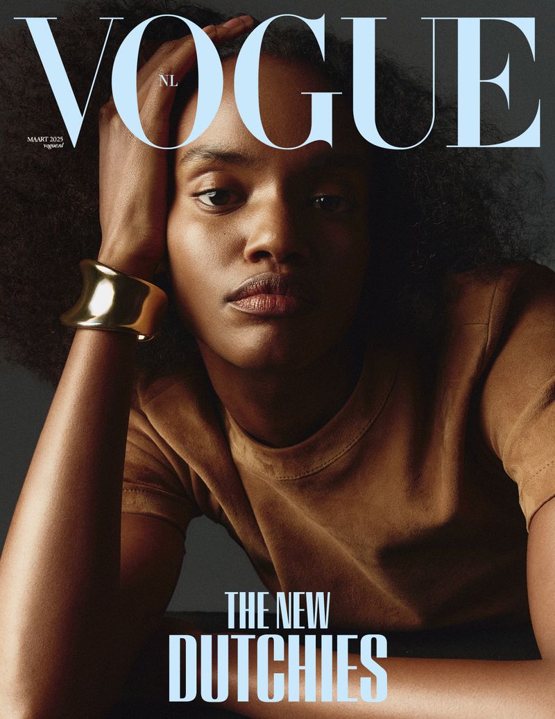 Vogue NL cover featuring a portrait of a Black woman with natural hair, wearing a brown t-shirt and large gold cuff bracelet.