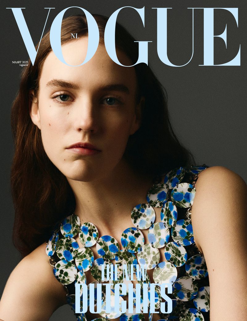 Vogue NL cover featuring a model with dark hair wearing a circular blue and white dress against a grey background.