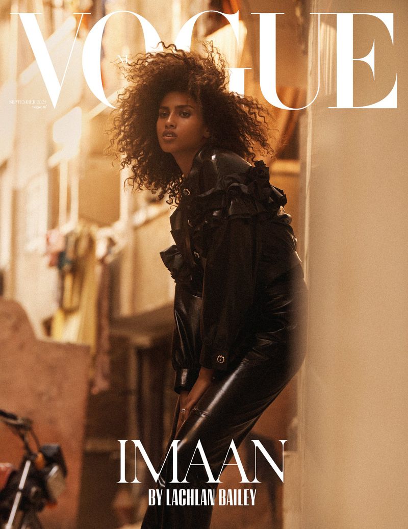 Vogue cover featuring a black female model, Imaam, wearing a black outfit with an urban background and warm lighting.