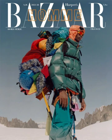 Magazine cover featuring a man in winter apparel with a large backpack, standing against a snowy mountain backdrop, blue sky, and magazine text.