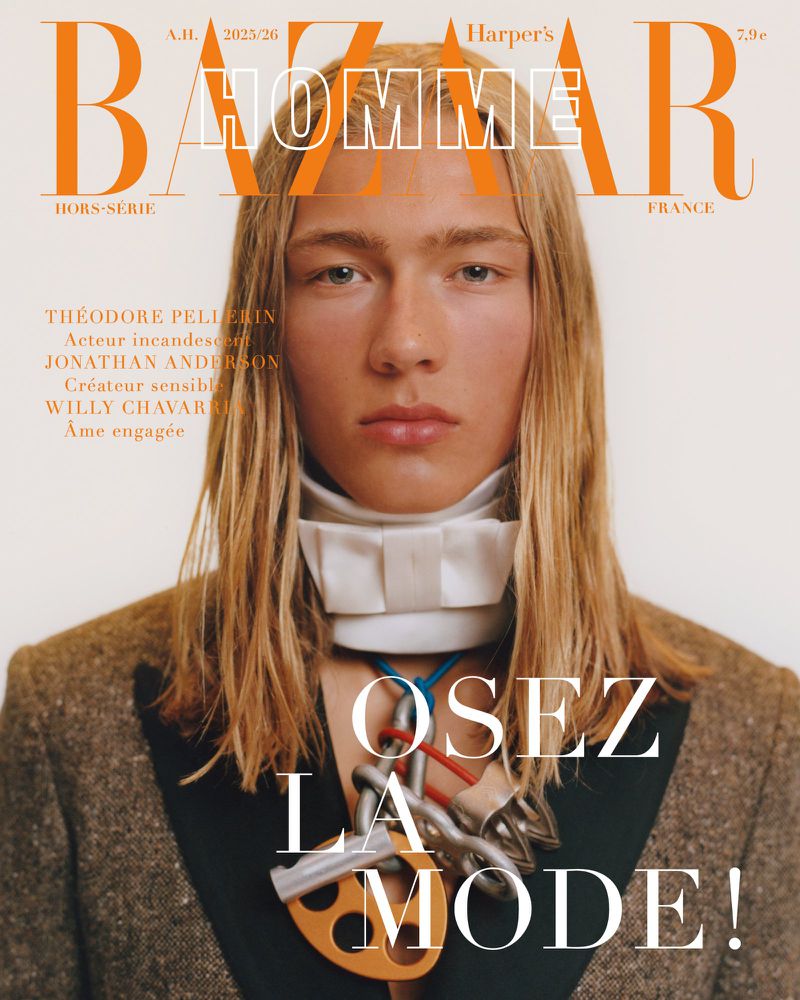 Magazine cover featuring a portrait of a young adult with long blonde hair, wearing a jacket and a unique necklace, set against a white background.