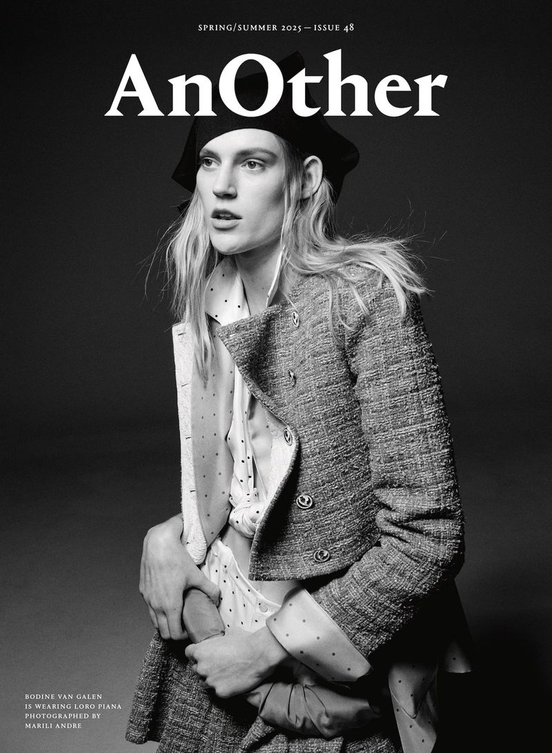 Black and white magazine cover shot of a model wearing a tweed jacket, beret, and spotted shirt with a grey-toned background.