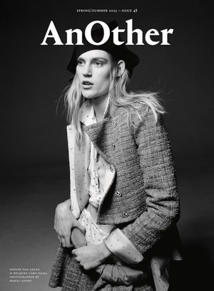 Model Bodine Van Galen wearing a textured tweed jacket and dark beret against a solid dark background for AnOther Magazine.