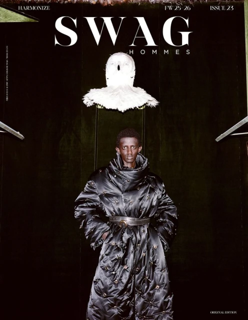 Editorial fashion shot of a Black man in a quilted black coat against a dark background, featured on the cover of SWAG Hommes magazine.