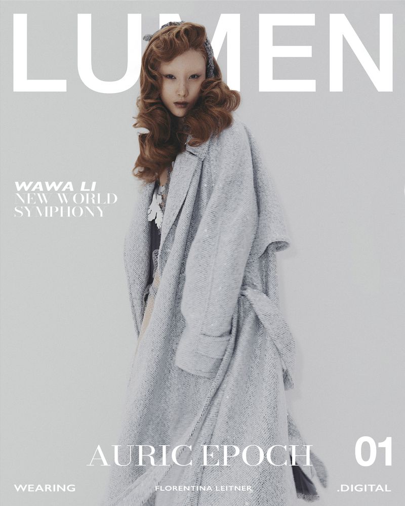 Magazine cover featuring a fair-skinned model in an oversized grey belted coat, complemented by brown hair and a cool grey background.
