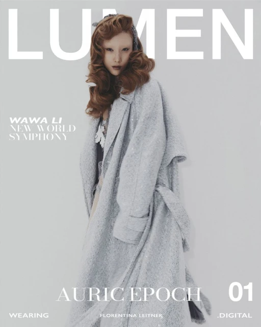 Magazine cover featuring a fair-skinned model in an oversized grey belted coat, complemented by brown hair and a cool grey background.