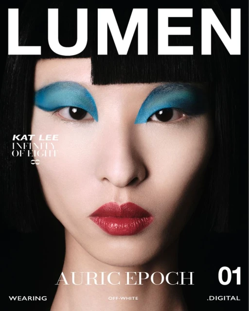 Close-up magazine cover featuring a woman with short black hair, turquoise eyeshadow, and red lipstick against a black background.