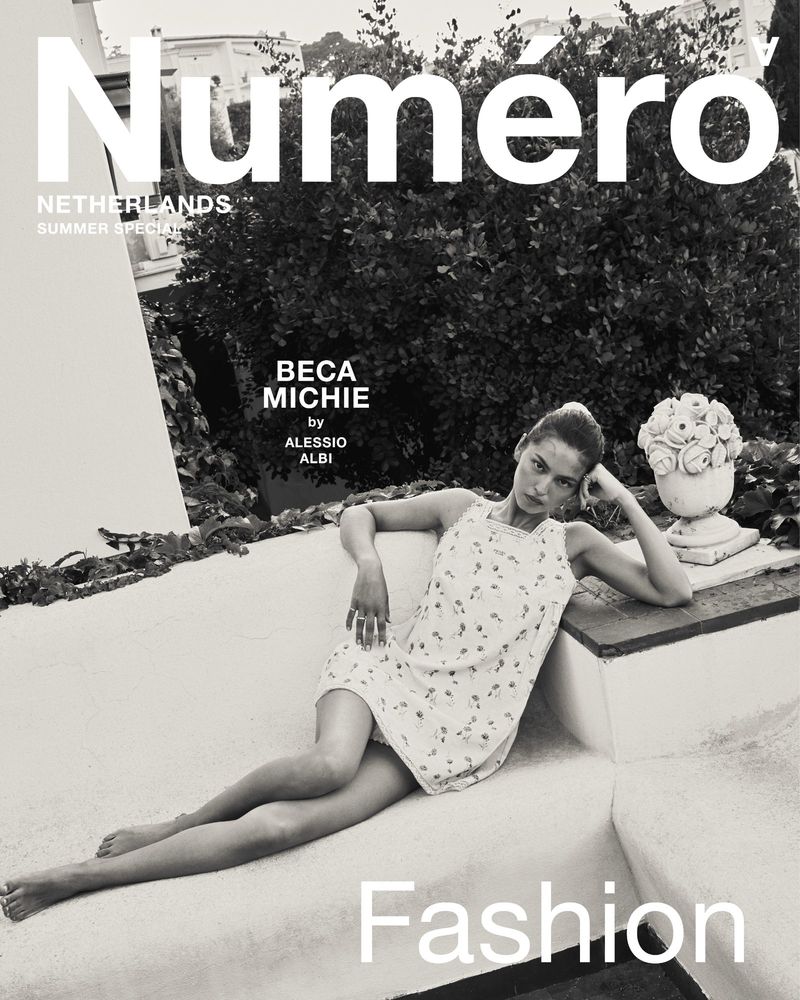Black and white fashion magazine cover features a woman in a floral dress reclining on a ledge next to a potted plant.