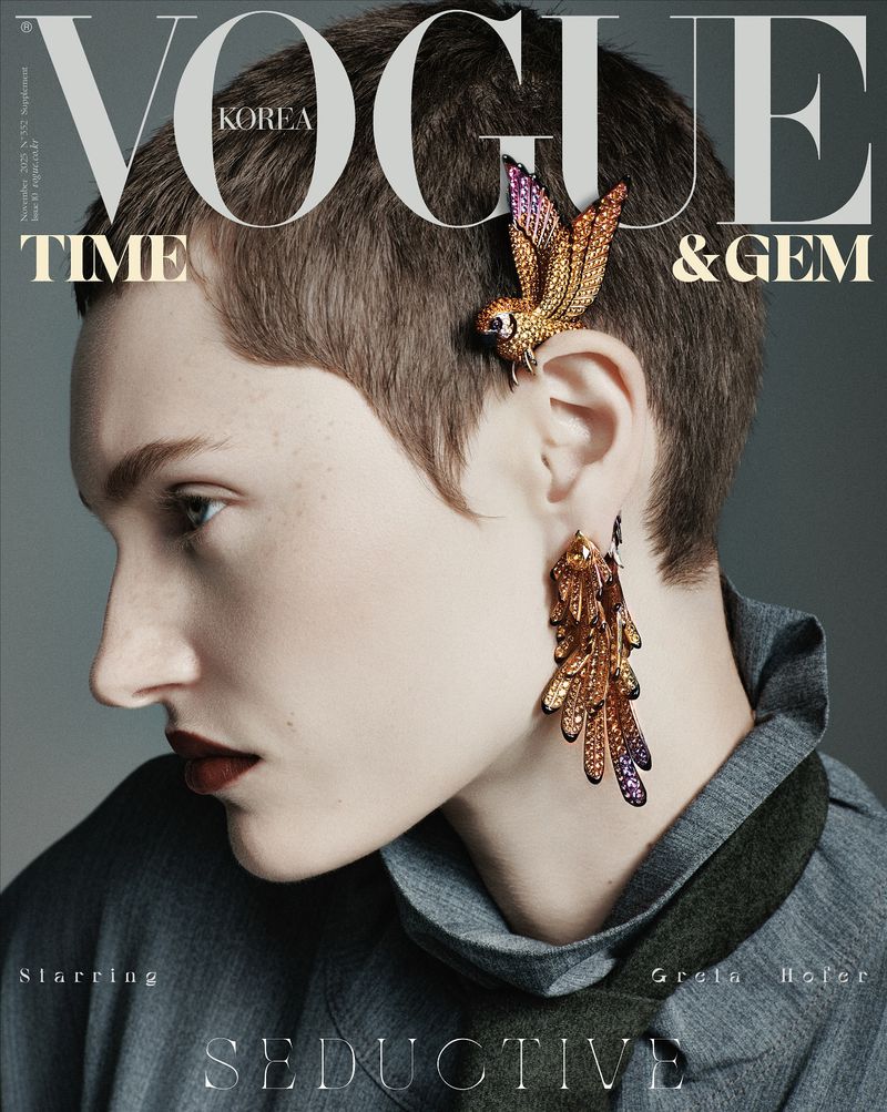 Vogue Korea magazine cover featuring a woman with short hair adorned with a bird hair clip and feather earrings against a grey backdrop.