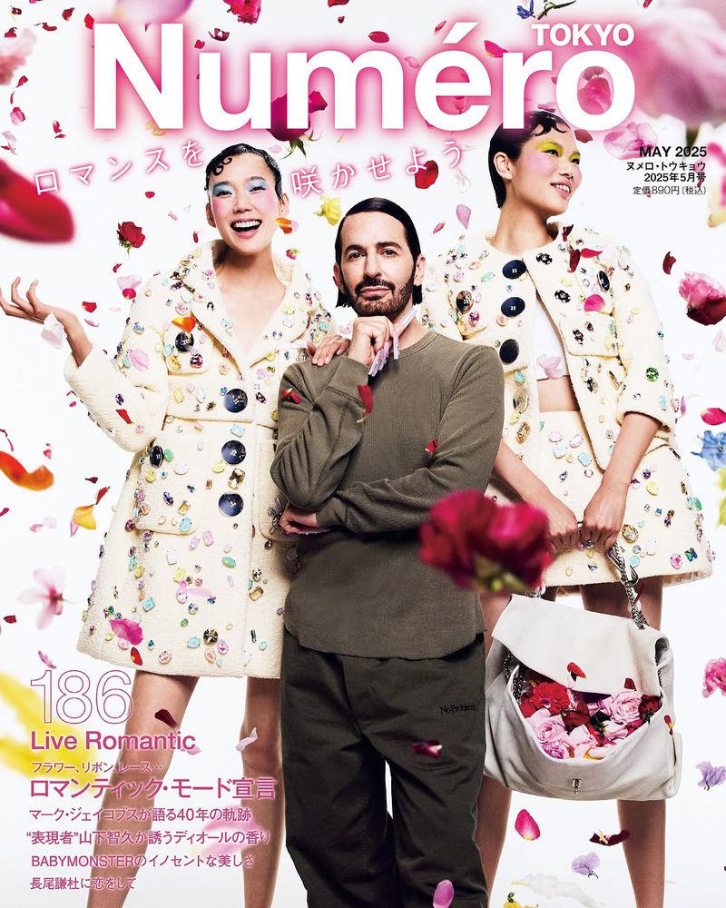 Magazine cover featuring two Asian models and Marc Jacobs surrounded by floating flower petals and holding a bag filled with roses.