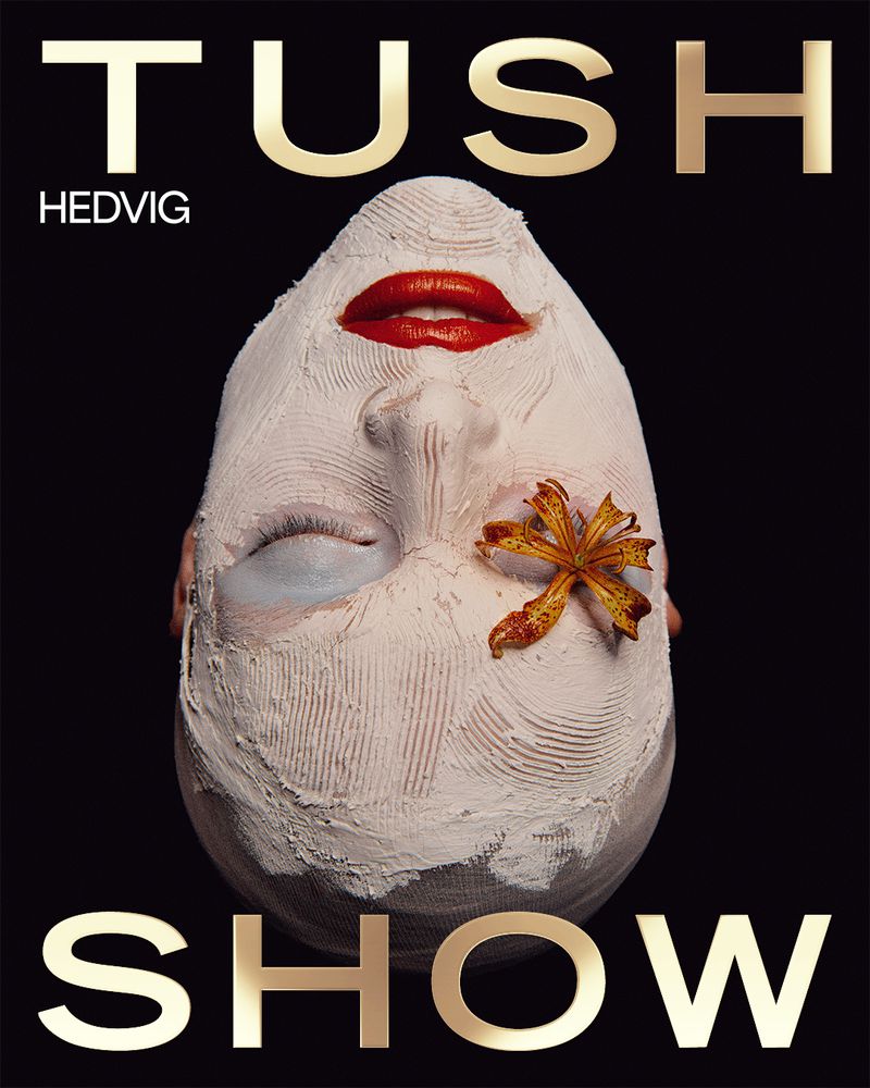 Fashion magazine cover featuring a face with makeup and floral embellishment, set against a stark black background with gold text.