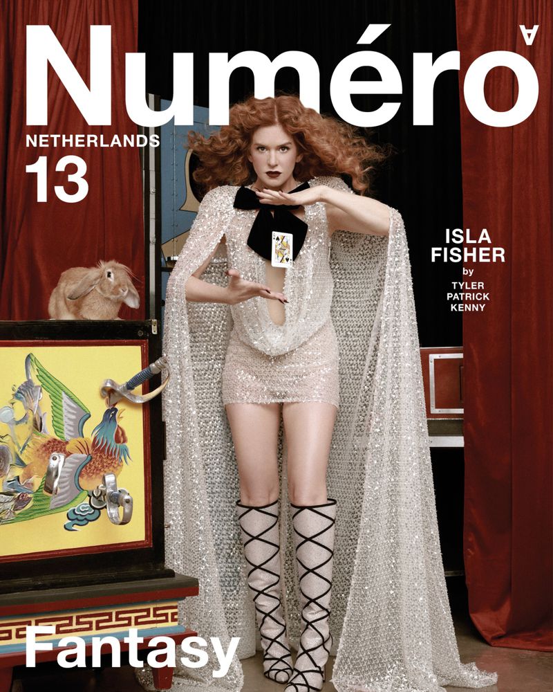Isla Fisher poses in a glittery dress and cape on the cover of Numero Netherlands. A rabbit and magic box are visible.