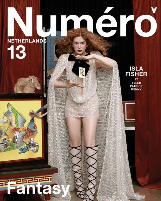 Isla Fisher poses in a glittery dress and cape on the cover of Numero Netherlands. A rabbit and magic box are visible.